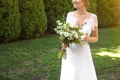 Bride in beautiful wedding dress with bouquet outdoors, closeup. Space for text