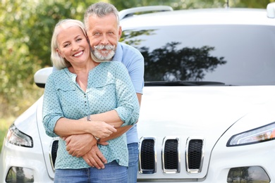 Happy senior couple posing near car outdoors