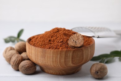 Photo of Nutmeg powder in bowl and seeds on white table