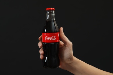 MYKOLAIV, UKRAINE - NOVEMBER 14, 2018: Woman holding bottle of Coca-Cola on black background