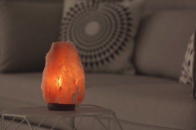 Photo of Himalayan salt lamp on table against blurred background