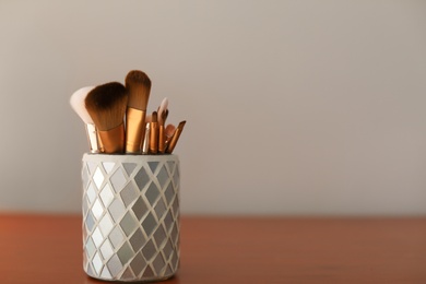 Holder with makeup brushes on table