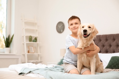 Cute little child with his pet on bed at home