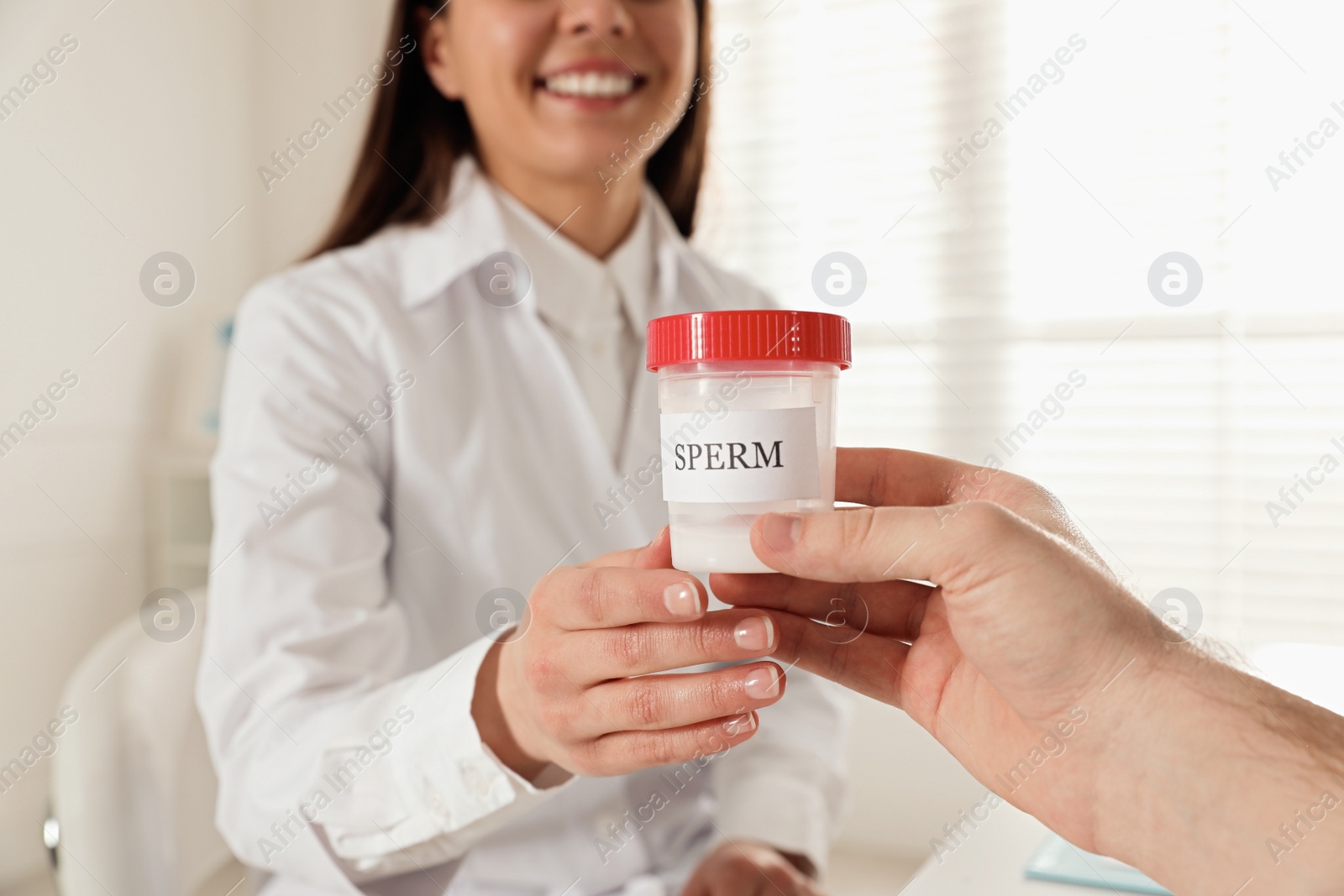 Photo of Donor giving container of sperm to doctor in hospital, closeup