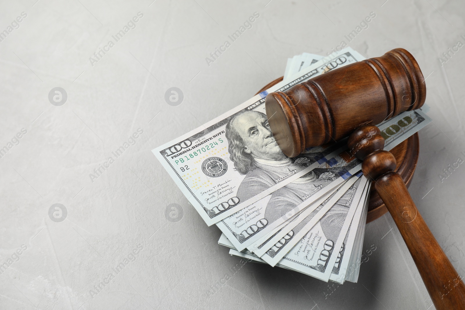 Photo of Judge's gavel and money on grey table. Space for text