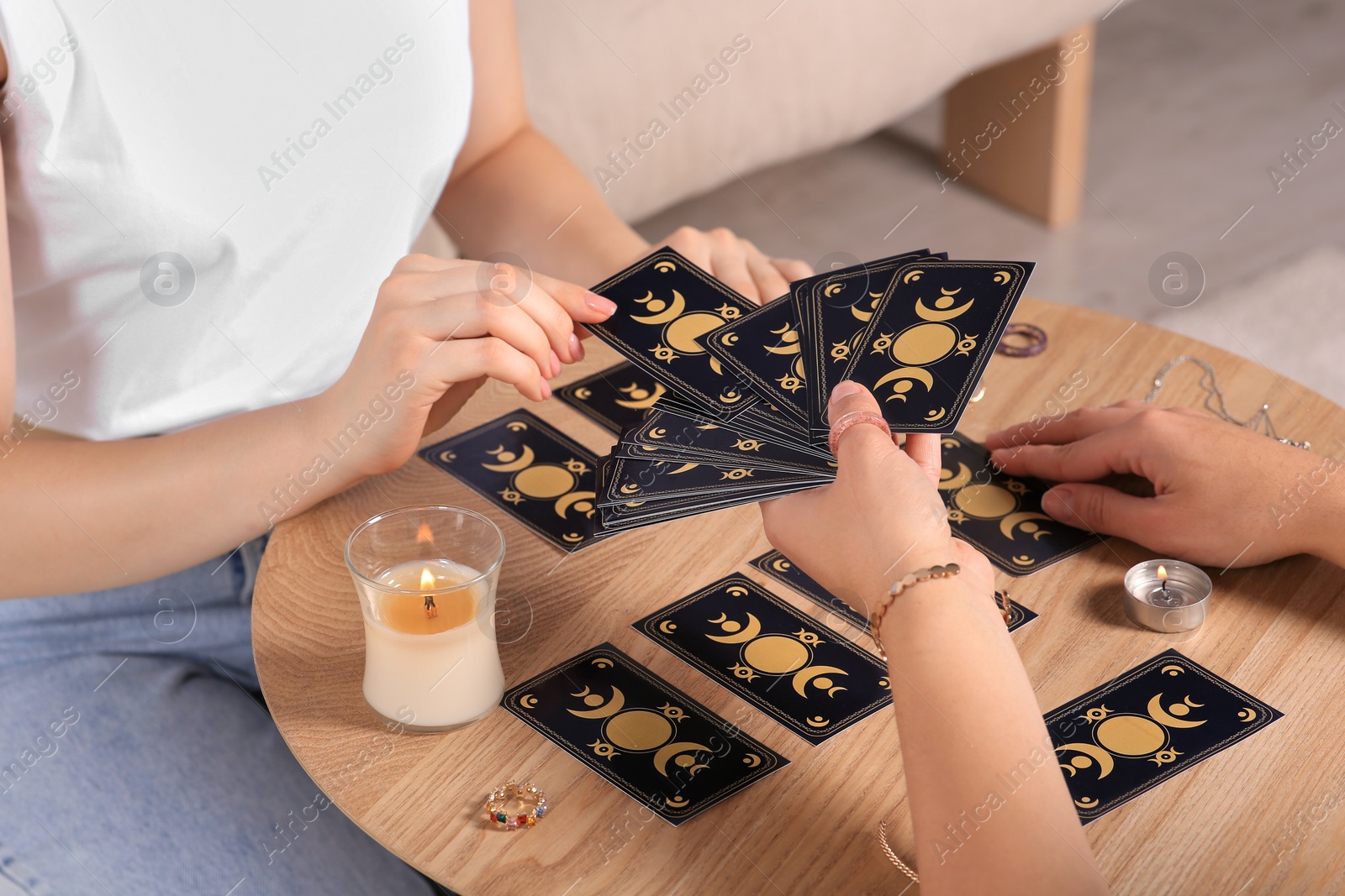 Photo of Woman pulling one tarot card at table indoors, closeup. Fortune telling