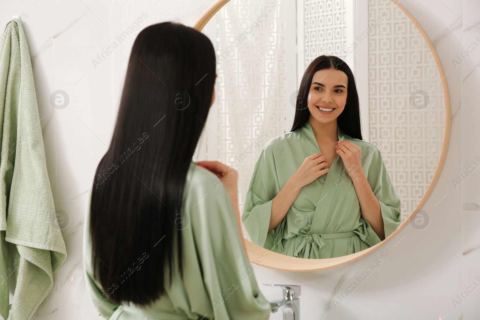 Photo of Beautiful young woman near mirror in bathroom