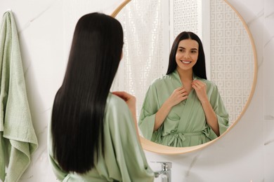 Photo of Beautiful young woman near mirror in bathroom