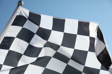 Photo of Checkered finish flag on light blue background, closeup