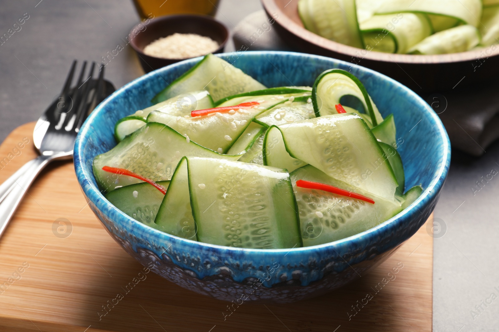 Photo of Dish with fresh cucumber salad on wooden board