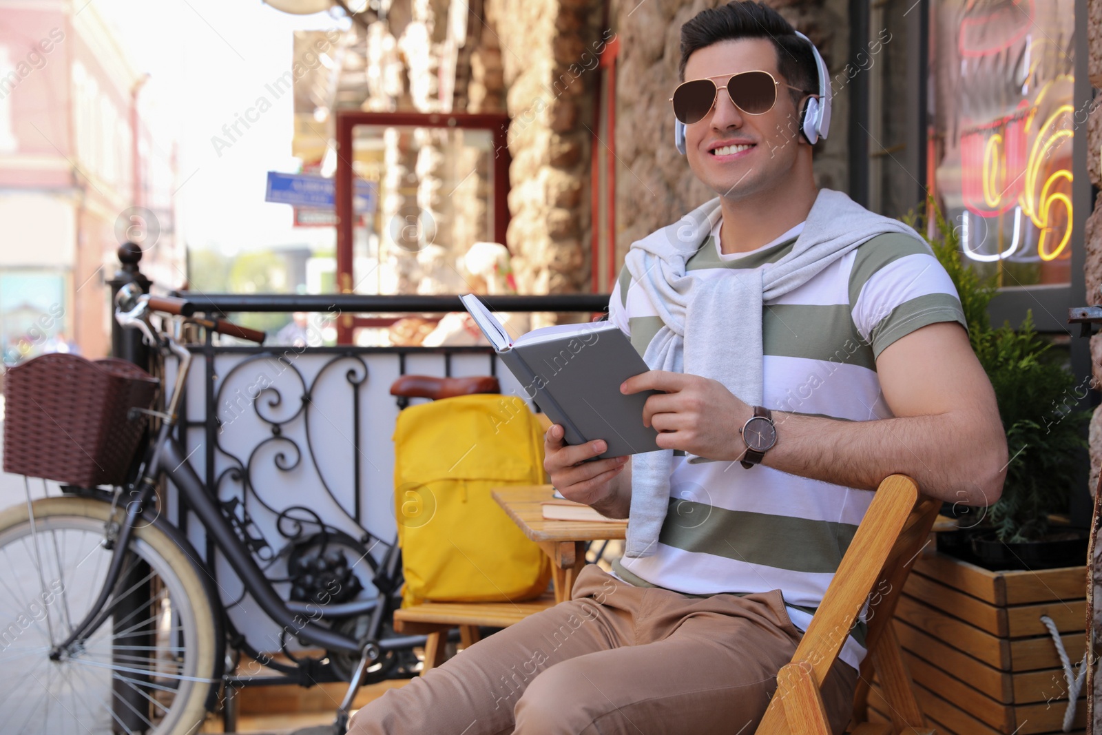 Photo of Handsome man reading book in outdoor cafe