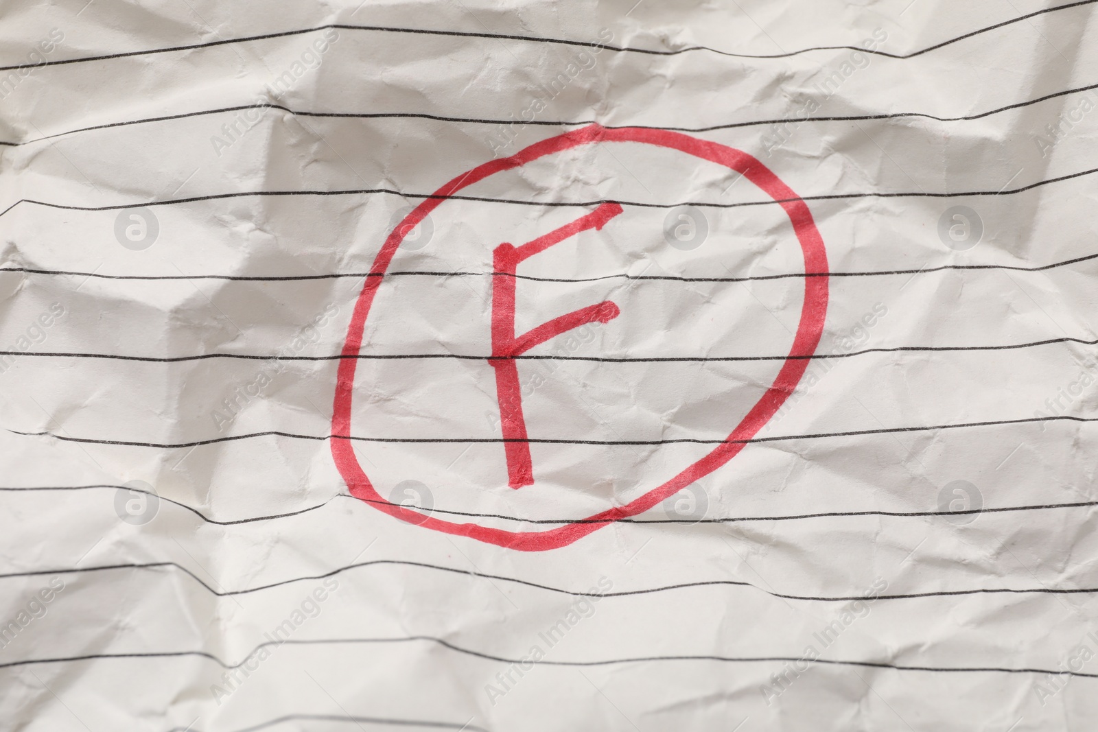 Photo of School grade. Red letter F on notebook paper, top view