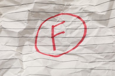 Photo of School grade. Red letter F on notebook paper, top view