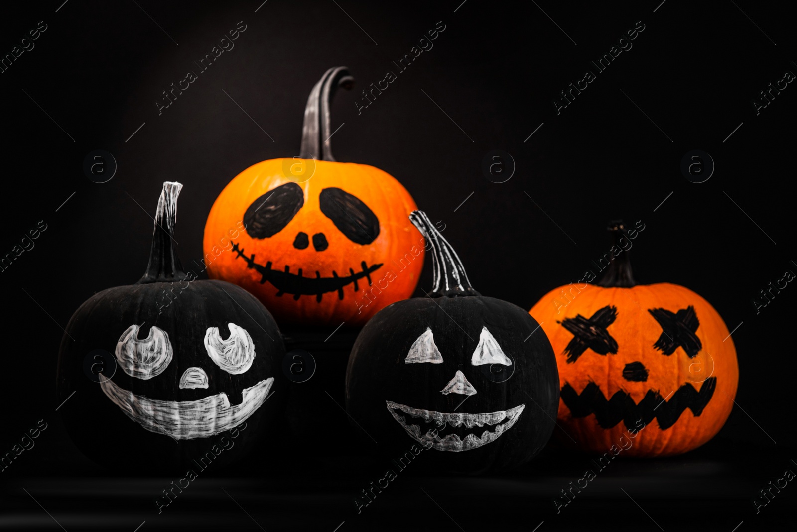 Photo of Halloween celebration. Pumpkins with drawn faces on table in darkness