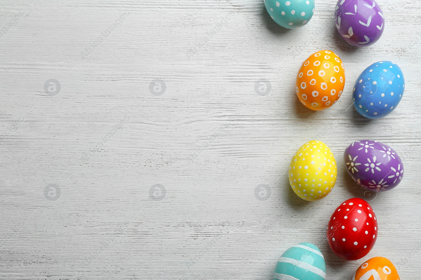 Photo of Flat lay composition of painted Easter eggs on wooden table, space for text