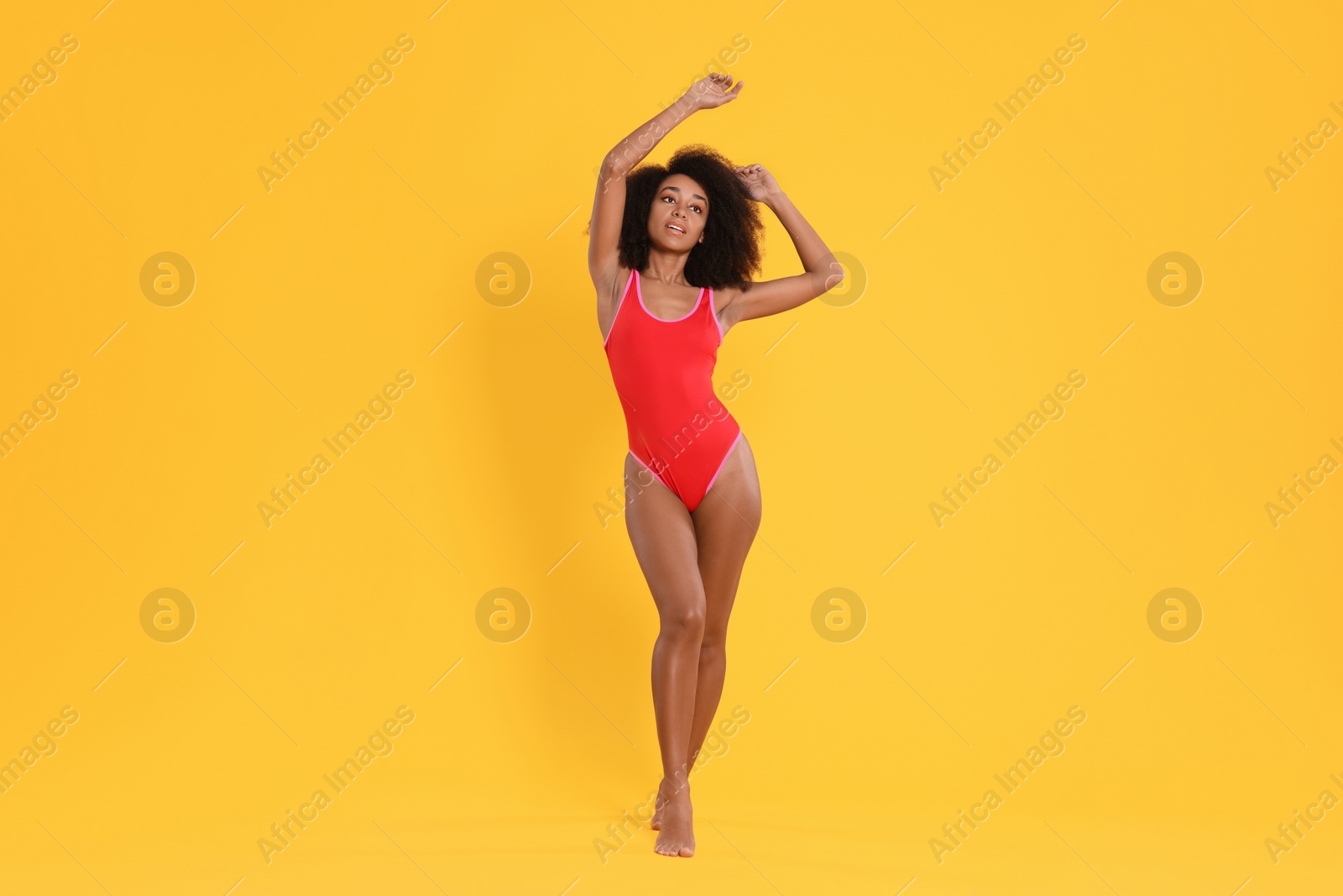 Photo of Beautiful woman in bright one-piece summer swimsuit on yellow background