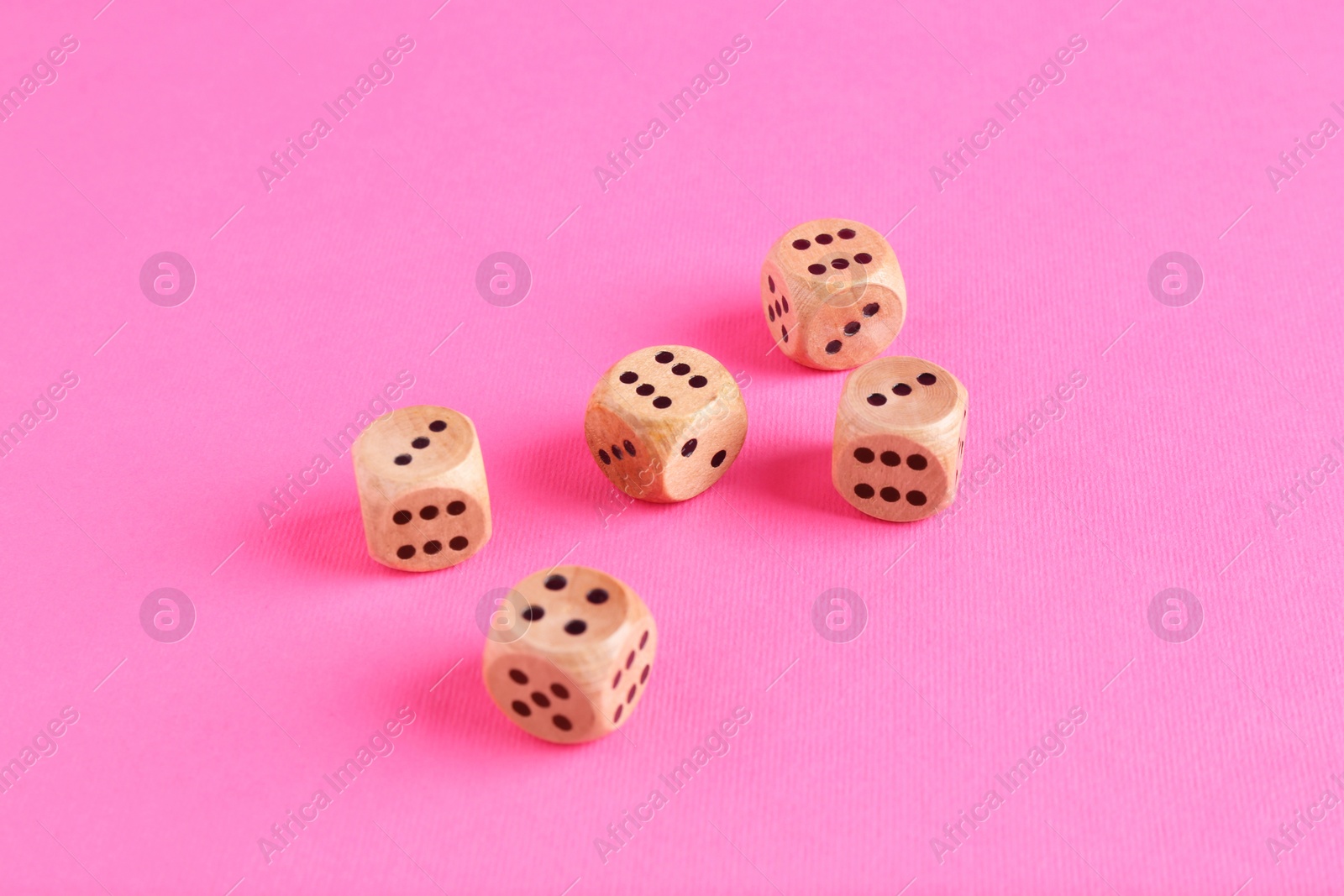 Photo of Many wooden game dices on pink background