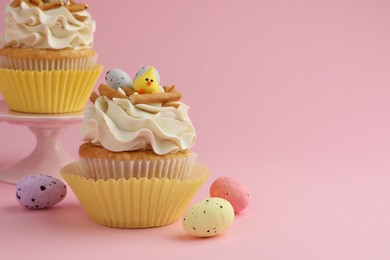 Photo of Tasty Easter cupcakes with vanilla cream and candies on pink background, space for text