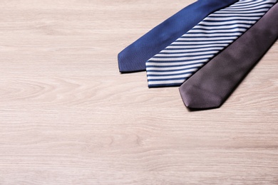 Different stylish neckties on wooden table, space for text