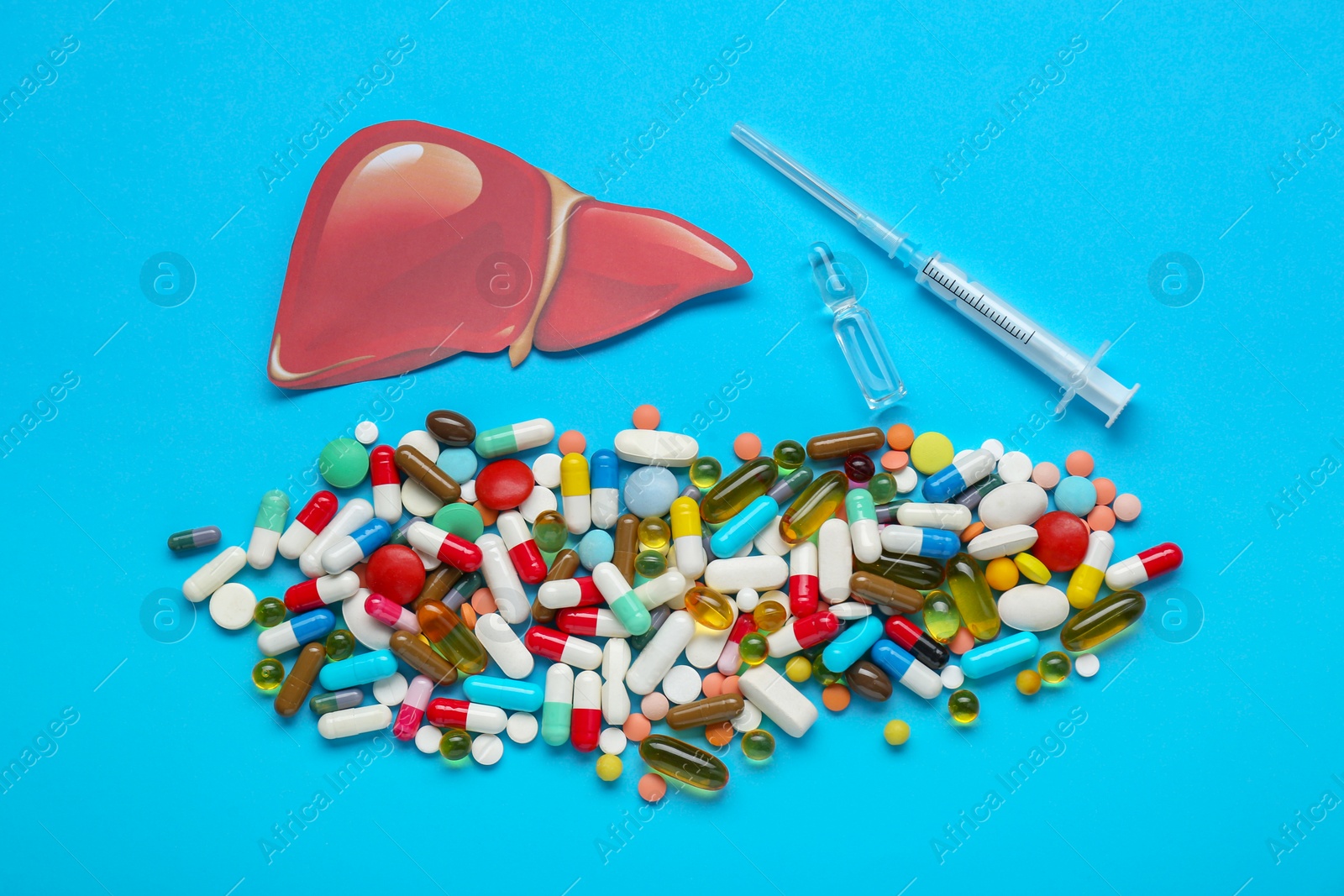 Photo of Paper liver, syringe, vial and pills on light blue background, flat lay. Hepatitis treatment