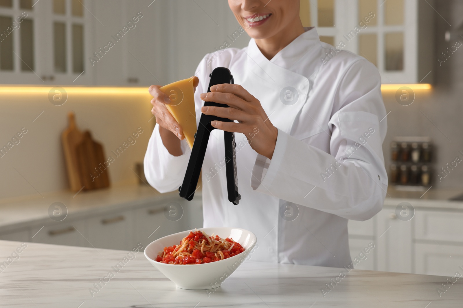 Photo of Professional chef grating cheese into delicious dish at white marble table indoors, closeup
