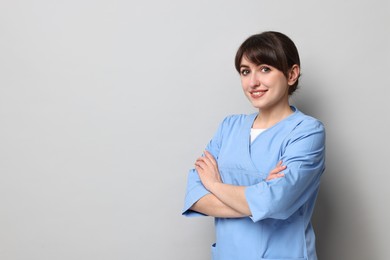 Photo of Portrait of smiling medical assistant with crossed arms on grey background. Space for text