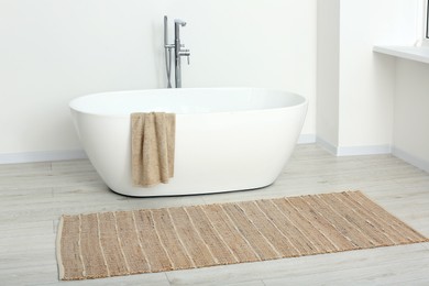 Photo of Beautiful white tub with towel in bathroom. Interior design