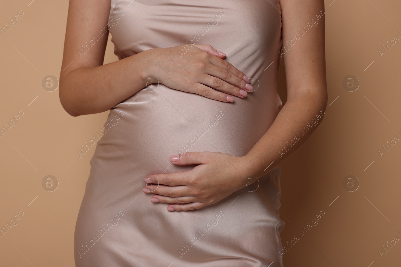 Photo of Pregnant woman in dress on beige background, closeup