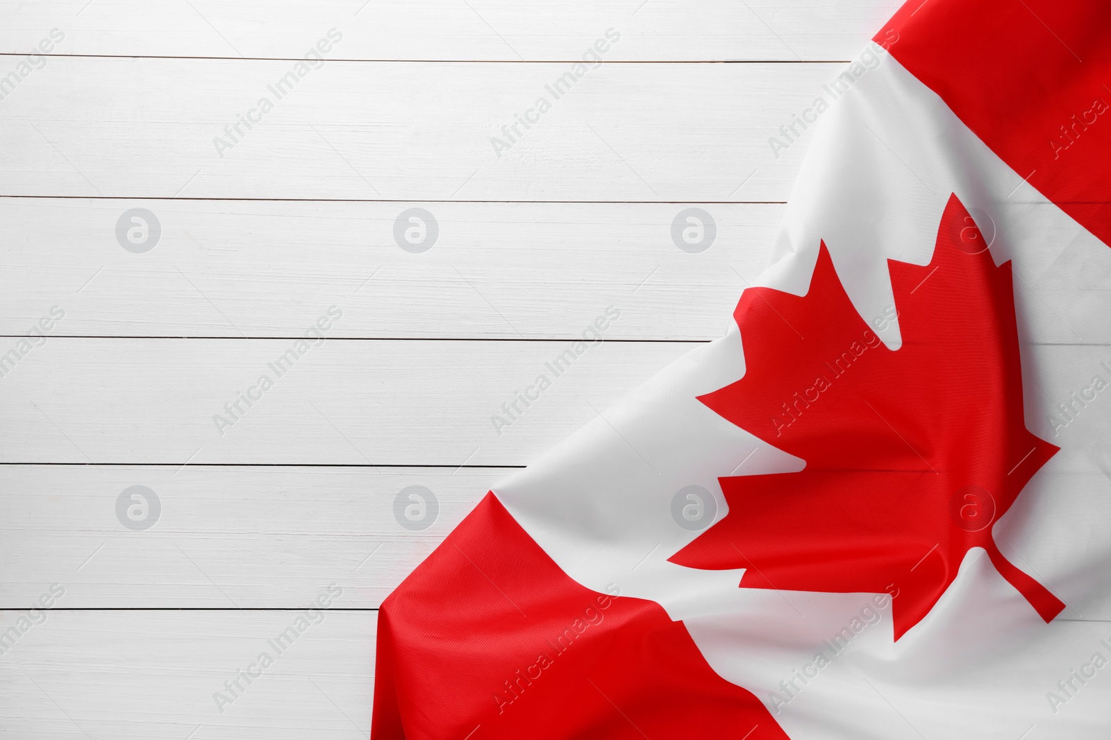 Photo of Flag of Canada on white wooden table, top view. Space for text