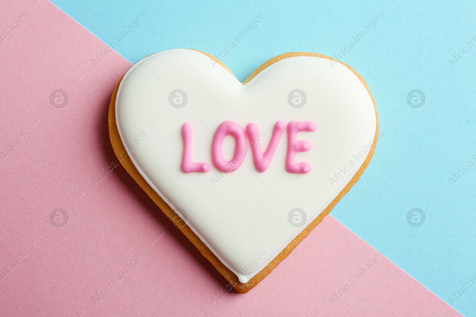 Photo of Decorated heart shaped cookie with word LOVE on color background, top view. Valentine's day treat