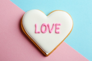 Photo of Decorated heart shaped cookie with word LOVE on color background, top view. Valentine's day treat