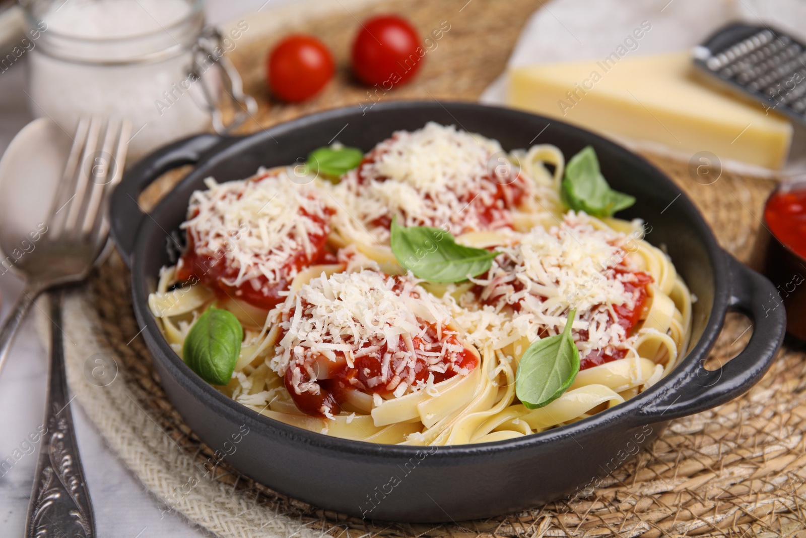 Photo of Delicious pasta with tomato sauce, basil and parmesan cheese on white marble table, closeup