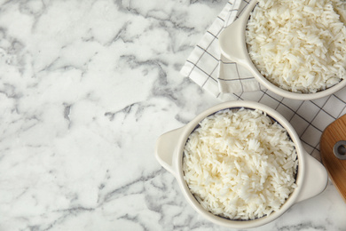 Photo of Bowls with tasty cooked rice on marble table, flat lay. Space for text