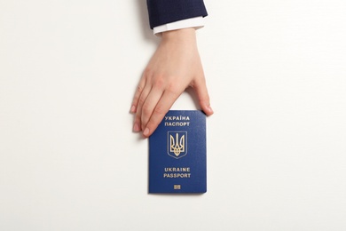 Photo of Woman with Ukrainian travel passport on light background, top view. International relationships