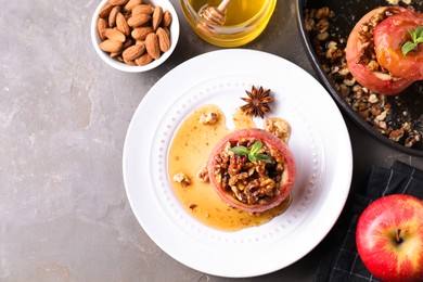 Photo of Tasty baked apples with nuts, honey and mint on gray textured table, flat lay. Space for text