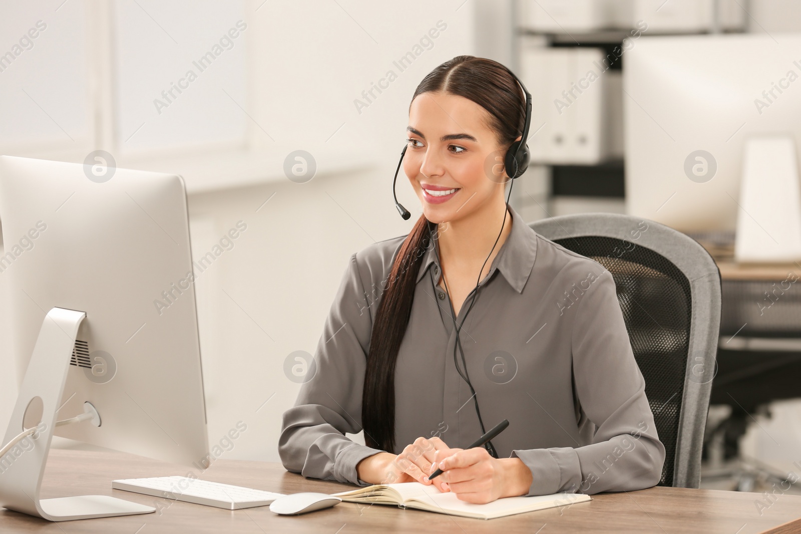 Photo of Hotline operator with headset and notebook working in office