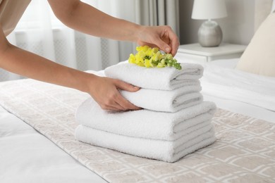 Woman putting flower on fresh towels in room, closeup
