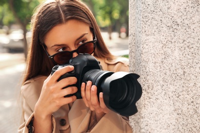 Private detective with camera spying near building on city street