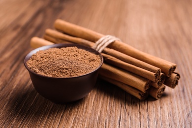 Photo of Cinnamon powder and sticks on wooden table