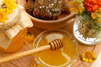 Photo of Delicious honey, combs and different flowers on wooden board