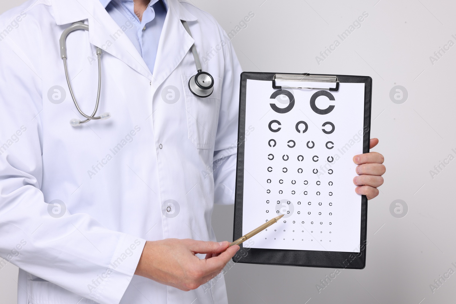 Photo of Ophthalmologist pointing at vision test chart on light background, closeup