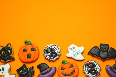 Photo of Different decorated gingerbread cookies on orange background, flat lay with space for text. Halloween celebration