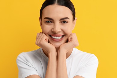 Beautiful woman with clean teeth smiling on yellow background