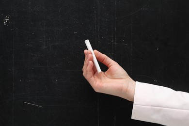 Teacher writing with chalk on black chalkboard, closeup. Space for text