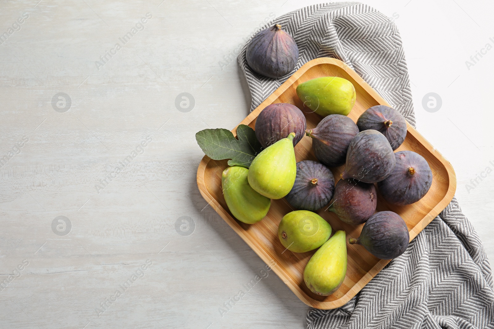 Photo of Plate with assorted ripe figs on light background, top view. Space for text