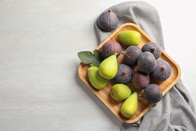 Photo of Plate with assorted ripe figs on light background, top view. Space for text