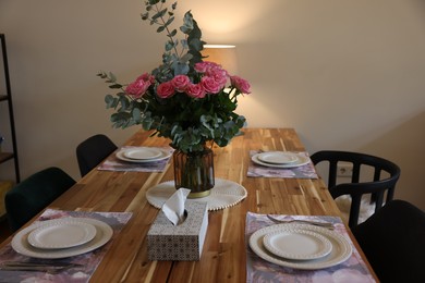 Photo of Beautiful table setting with bouquet and napkins indoors. Roses and eucalyptus branches in vase