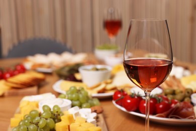 Photo of Glass of rose wine and appetizers served on wooden table, selective focus. Space for text