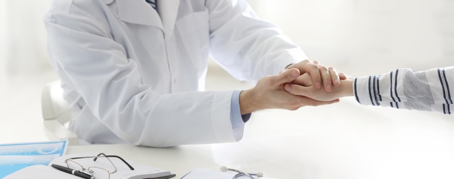 Doctor consulting patient at desk in clinic, closeup. Banner design