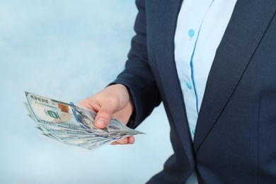 Photo of Woman holding bunch of dollar banknotes on color background, closeup